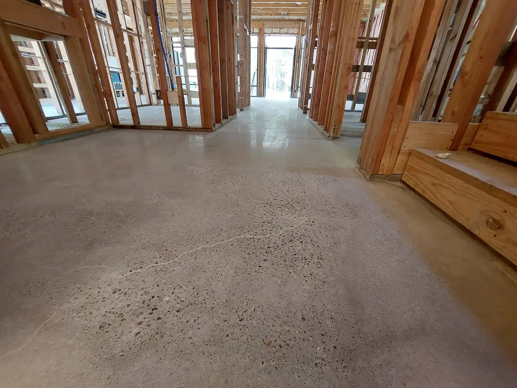 Warm exposed aggregate polished concrete floor with stone visible through the surface, in a house under construction